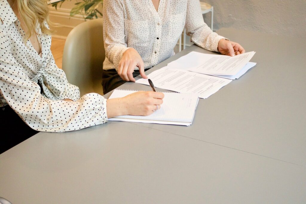 two women sitting at a table with paperwork